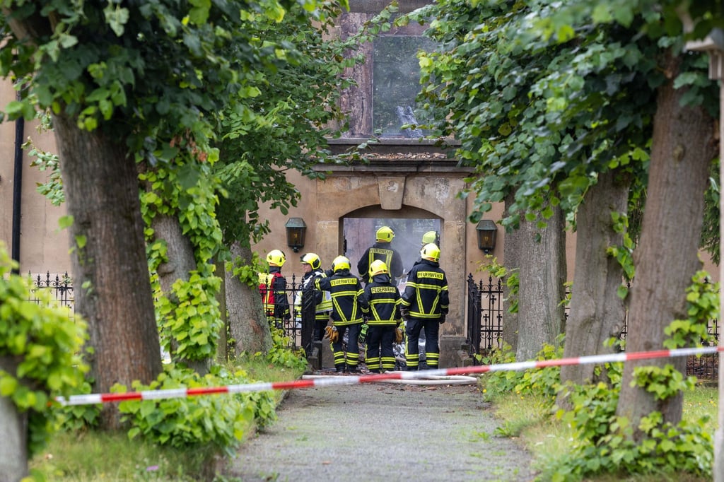 Feuerwehrleute sind an der Stelle der brennenden Stadtkirche im Einsatz.