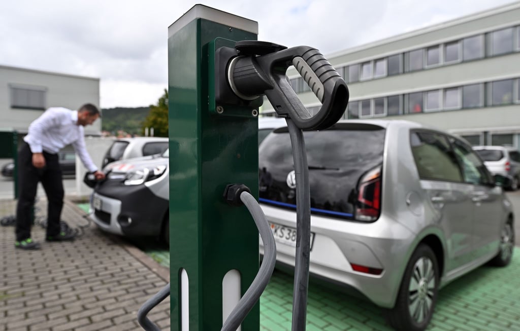 Wolfgang Hillesheim, Sachbearbeiter in Jena, steckt den Ladestecker eines E-Autos ein.