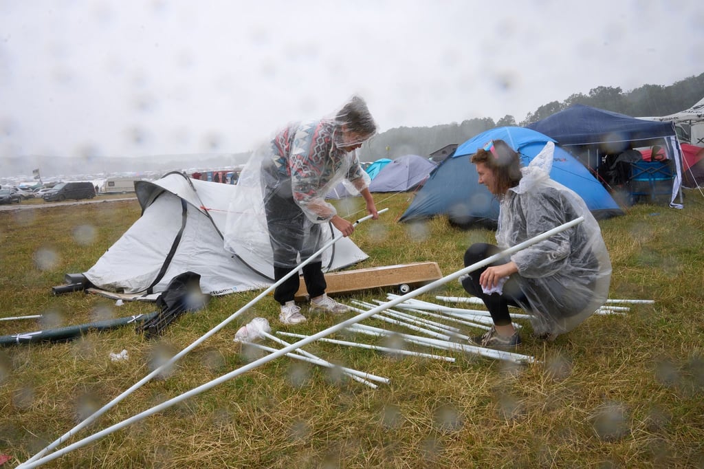 Zwei Fans bauen auf dem Campinggelände des Technofestivals „Nature One“ bei strömendem Regen ihr Zelt auf.