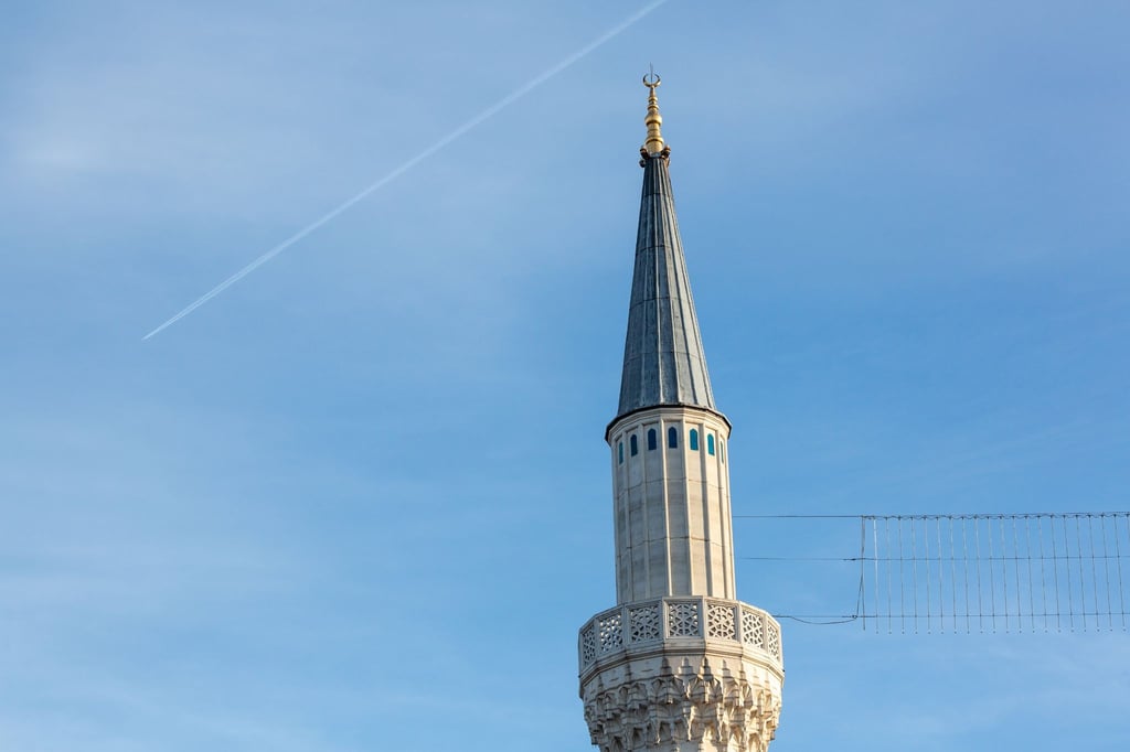 Das Minarett einer Moschee wird von der Sonne angestrahlt.