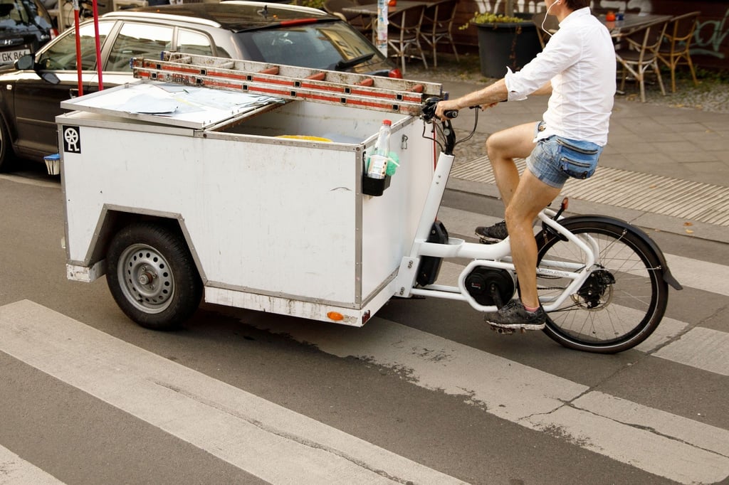 Ein Mann fährt mit einem Lastenrad in einer Stadt.