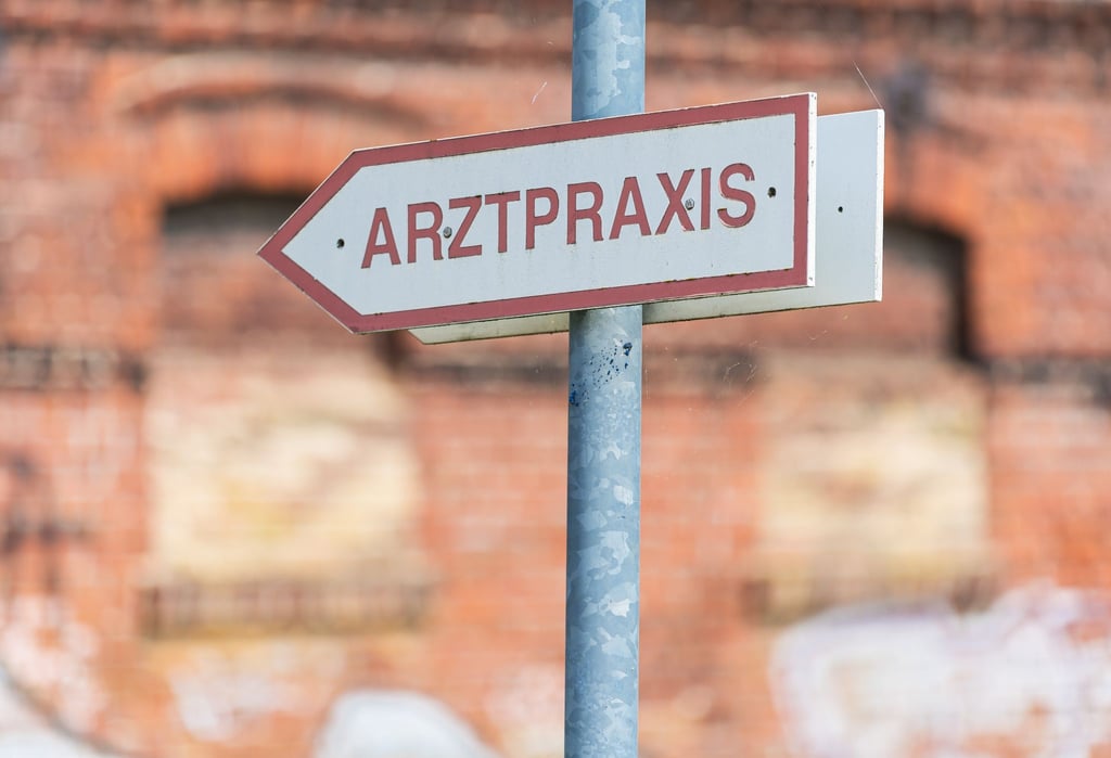 Ein Schild weist den Weg zu einer Arztpraxis.