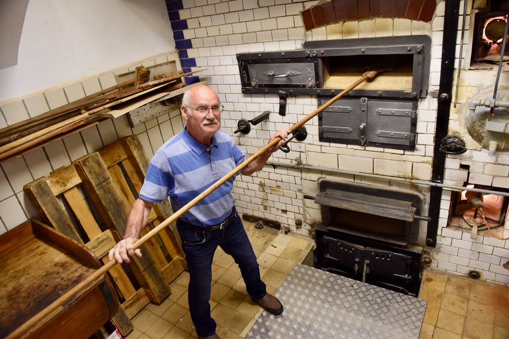 Vorsitzender Reinhard Retzer zeigt die Funktionsweise des historischen Backofens, der 1879 als Herzstück in die Bäckerei eingebaut wurde und heute noch zum Schaubacken benutzt wird.
