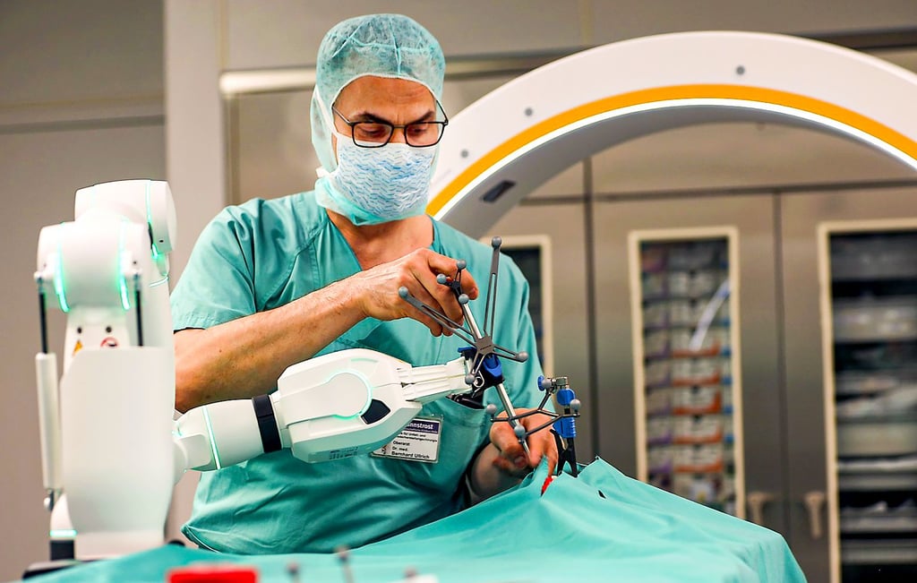 Oberarzt Bernhard Ullrich  bei der Simulation eines Eingriffs – unterstützt von einem  Roboterarm.  