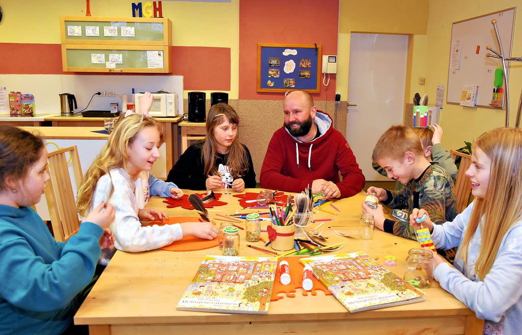 Tobias Just sitzt mit Kindern aus dem Hort der benachbarten Grundschule an einem Tisch im Mehrgenerationenhaus in Görzig.