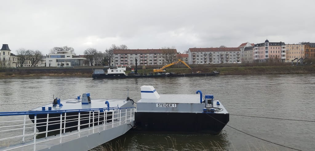 Vom Schiff aus ist der Bagger hier am Ufer der Elbe in Magdeburg tätig.