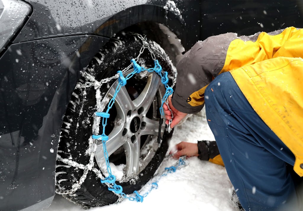 Mit geübter Hand: Das Anlegen von Schneeketten üben Autofahrer besser vor dem Ernstfall. Um die Hände vor Kälte und kleinen Verletzungen zu schützen, sollte man zudem Handschuhe nutzen.