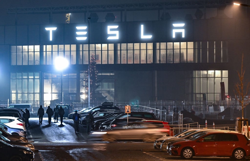 Mitarbeiter gehen am frühen Morgen auf einem Parkplatz zum Werk des US-Elektroautobauers.
