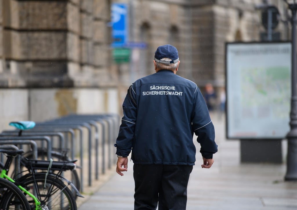 Ein ehrenamtlicher Mitarbeiter der Sächsischen Sicherheitswacht läuft einen Fußweg in der Innenstadt entlang.