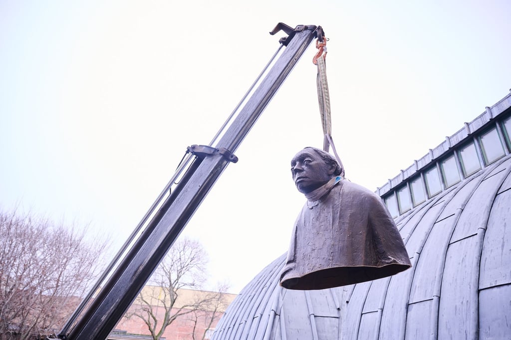 Der obere Teil der zersägten Bronzeplastik Käthe Kollwitz von Gustav Seitz hängt an einem Kran.