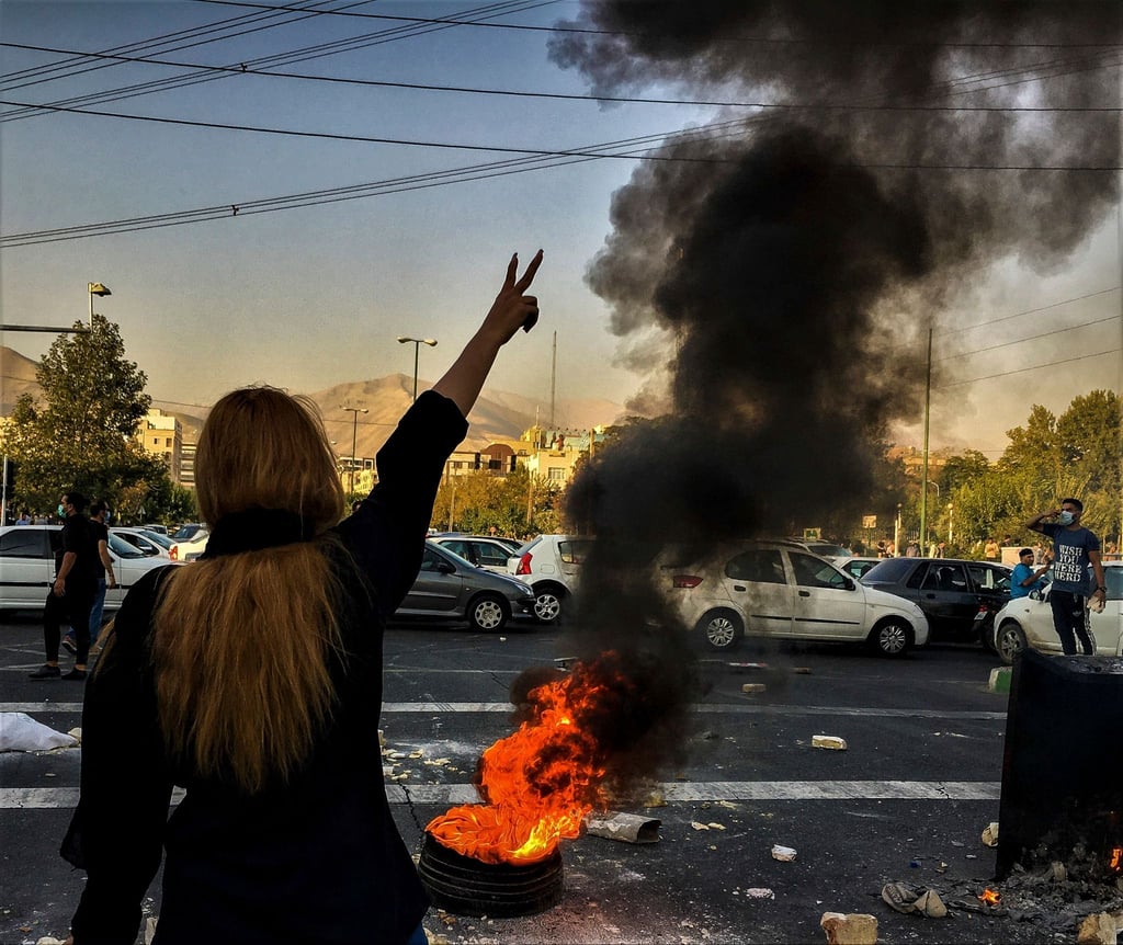 Nach dem Tod der 22-jährigen Mahsa Amini steht eine Frau während einer Demonstration in Teheran vor einem brennenden Autoreifen.