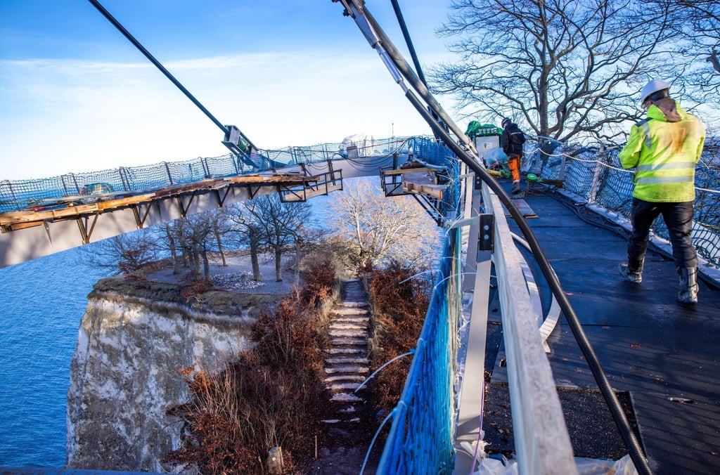 Auf der zukünftigen Besucherbrücke Königsweg wird die Absenkung des Rundwegs über dem Kreidefelsen „Königsstuhl“ vorbereitet. Ab dem Frühjahr 2023 könnte die an einem Mast über dem 118 Meter hohen Königsstuhl schwebende Konstruktion für Besucher eröffnet werden.