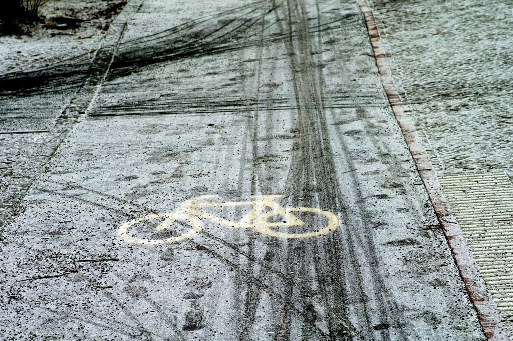Fahrräder haben auf einem Radweg Spuren im Schnee hinterlassen.