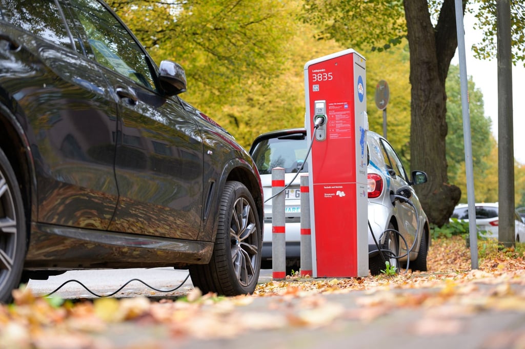 Ein SUV und ein Kleinwagen stehen mit angeschlossenen Ladekabeln an einer öffentlichen Ladesäule.