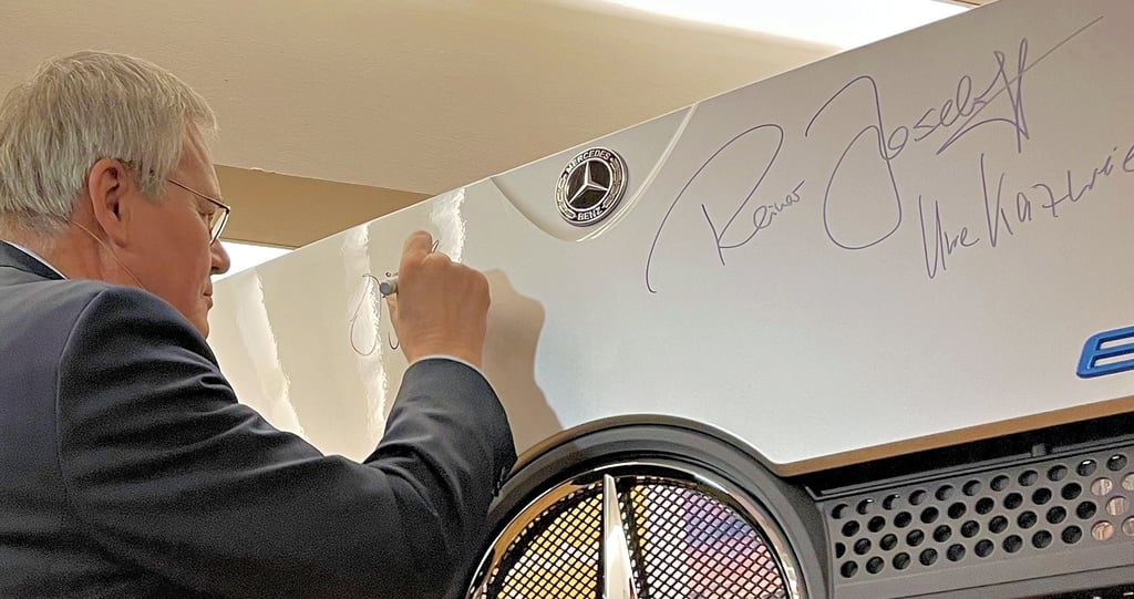 Jörg Howe, Generalbevollmächtigter politische Außenbeziehungen & globale Kommunikation Daimler Truck AG, unterschreibt hier auf der Lkw-Frontschürze, die im Halberstädter Ratssaal für die symbolische Vertragsunterzeichnung zwischen Land, Stadt und Unternehmen aufgestellt ist.