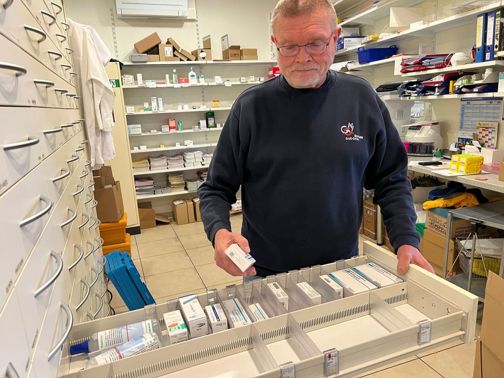 Ein Apotheker an der fast leeren Medikamenten-Schublade.