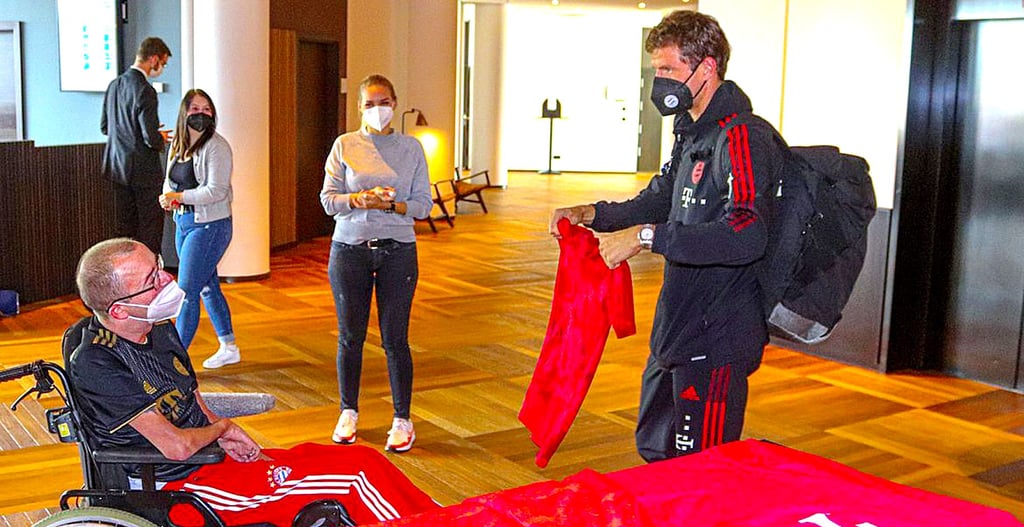 Der schwerkranke Bayernfan Tommy bekommt vom Bayern-Spieler Thomas Müller 2021 anlässlich einer Fahrt mit dem Wünschewagen nach München ein T-Shirt.