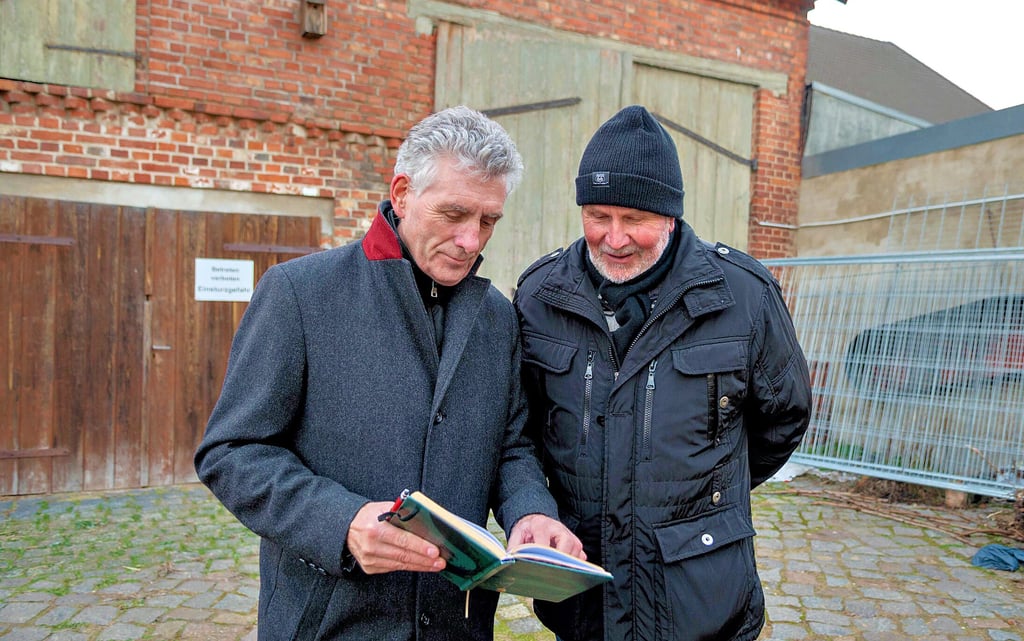 Manfred Behrens(l.) und Heinz Reckler schauen sich vor der maroden Scheune die Pläne für die mögliche Sanierung an. DIe beiden Männer hoffen auf eine schnelle Lösung.