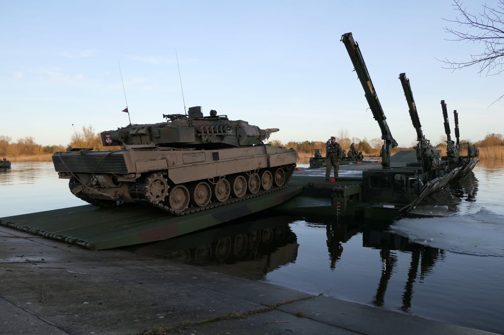Ein Panzer Leopard 2 setzt auf einer aus Schnellschwimmbrücken gefertigte Fähre bei einer Übung über.