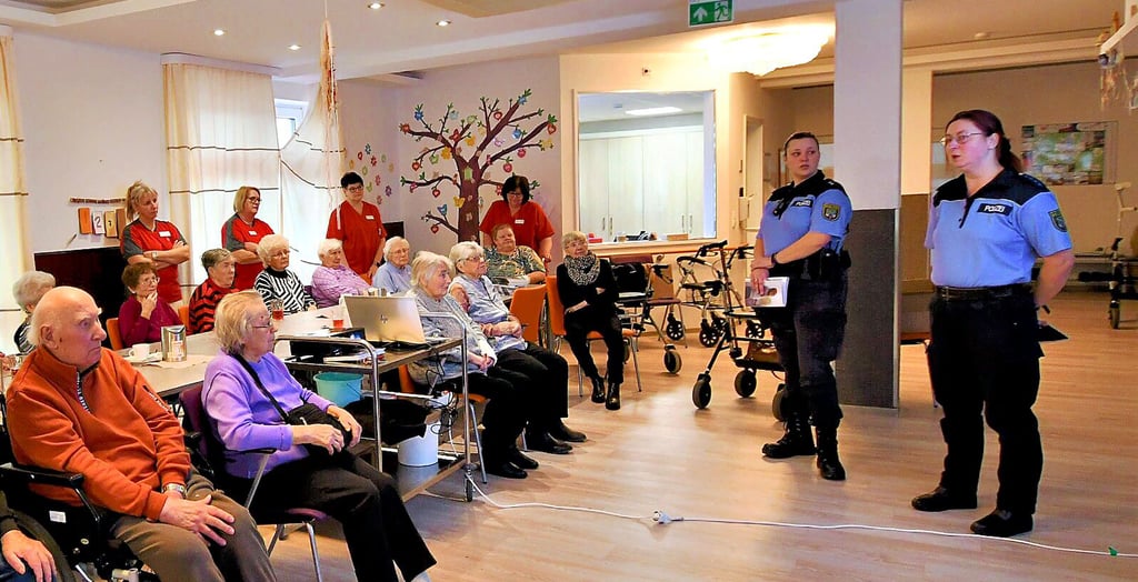 Polizeihauptmeisterin Alexandra Frenzel (r.) und Polizeioberkommissarin Janina Vanak (2. v. r.) hatten aufmerksame Zuhörer bei ihrer Infoveranstaltung zum Thema Enkeltrick in der Tagespflege des DRK in Gräfenhainichen