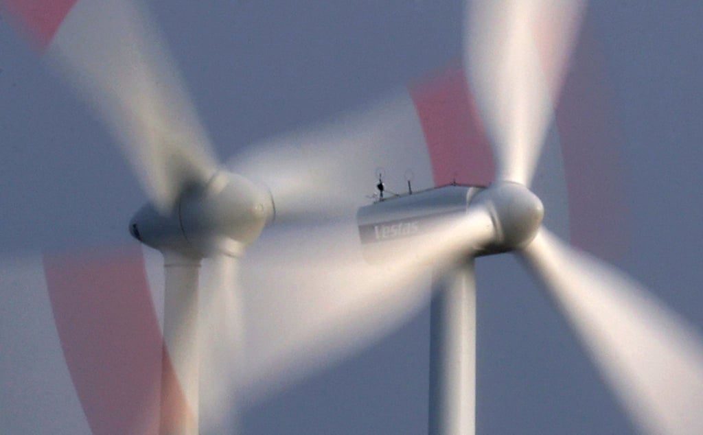 Zwei Windräder drehen sich bei heftigem Wind vor wolkenüberzogenem Himmel.