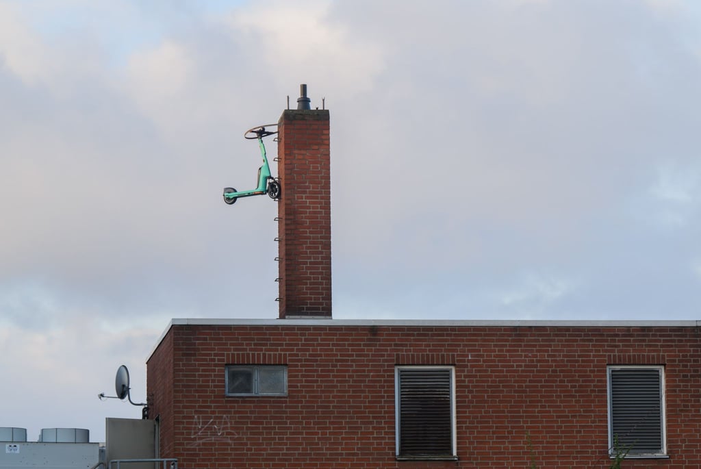 Ein E-Scooter des Anbieters Tier hängt an einem Schornstein eines Supermarktes.