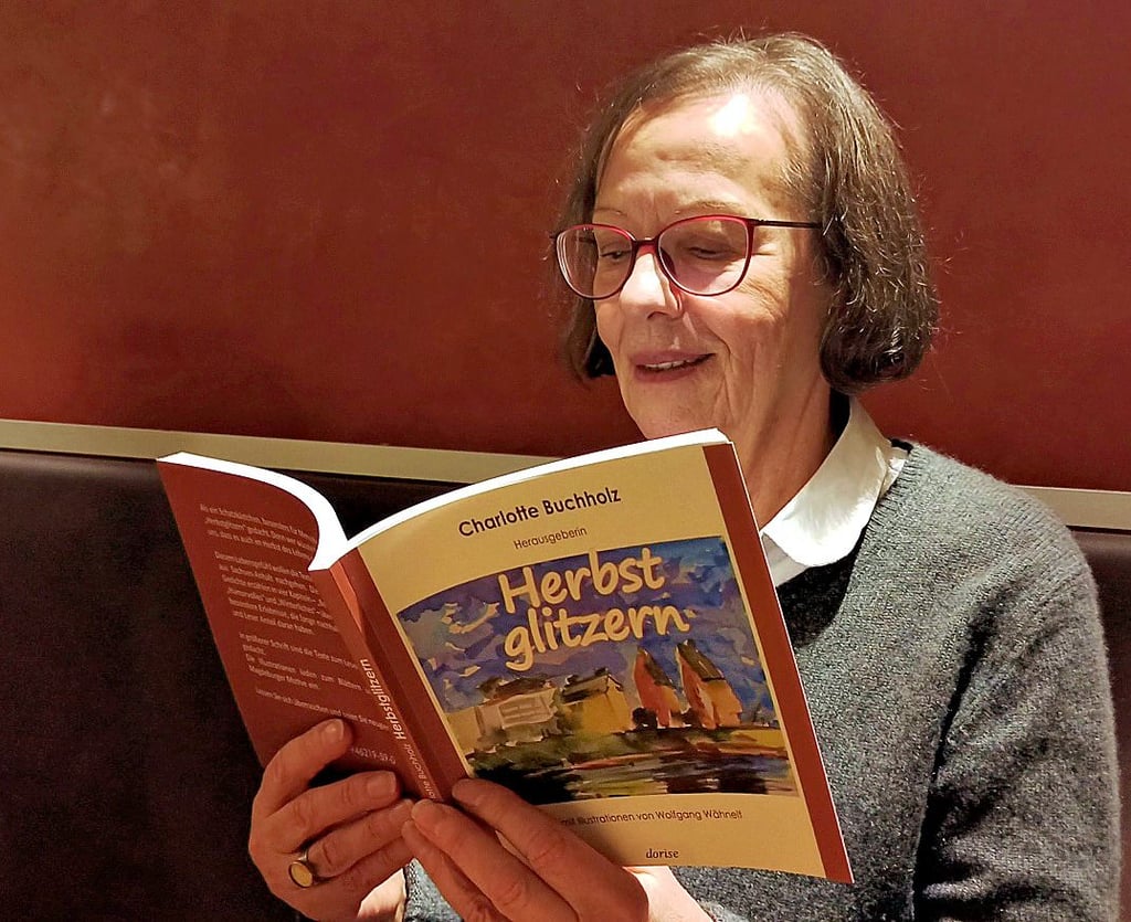 Ursula Günther alias Charlotte Buchholz blättert in ihrem Buch „Herbstglitzern“, das in großer Schrift erstellt wurde.