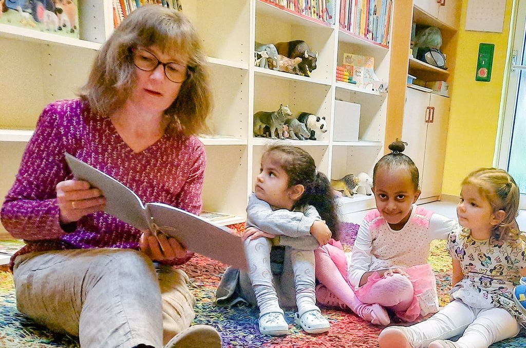 Sprachfachkraft Manuela Knittel liest den Mädchen Islam, Delina und Katharina (v.li.) etwas aus einem selbst entworfenen Kinderbuch vor.