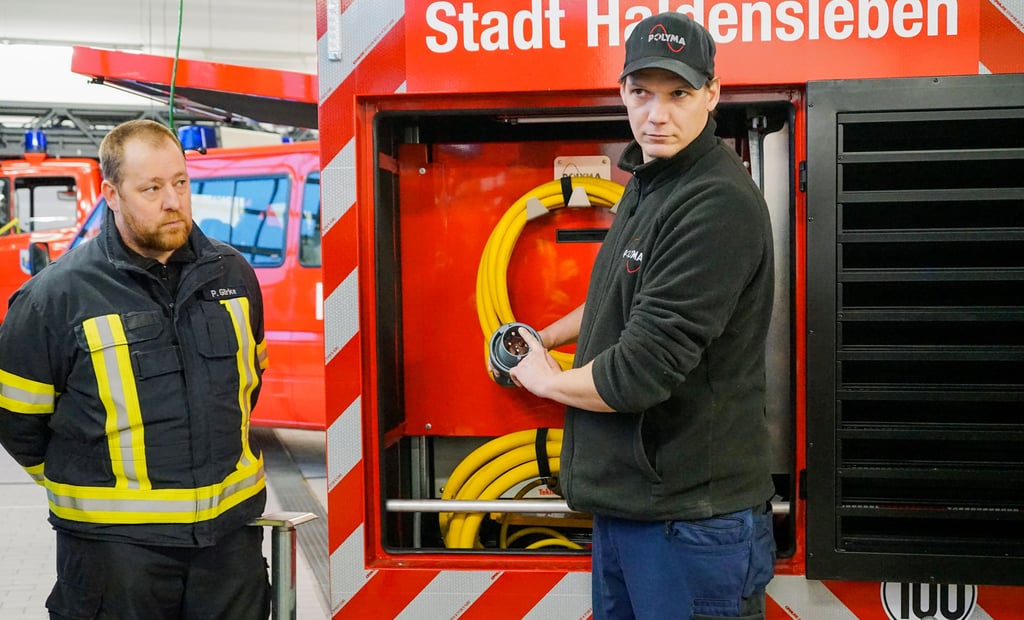 Alexander Deich (rechts) von der Firma Polyma Energiesysteme aus Kassel weist die Kameraden der Freiwilligen Feuerwehr Haldensleben in den neuen Notstromaggregator ein.