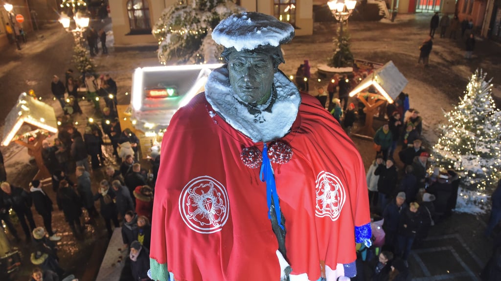 Auf dem Weihnachtsmarkt in Eisleben erstrahlt das Lutherdenkmal in vollem Glanz.