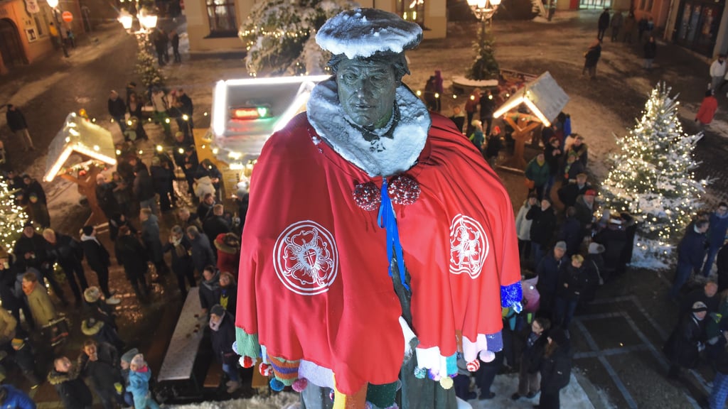 Auf dem Weihnachtsmarkt in Eisleben erstrahlt das Lutherdenkmal in vollem Glanz.
