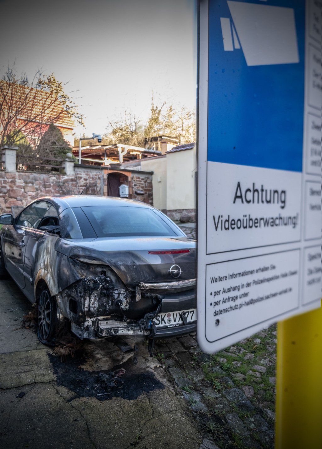 Das in Brand gesetzte Auto von Holger B. vor dessen Grundstück in Brachwitz. Die Polizei überwacht sein Haus mit einer Kamera.