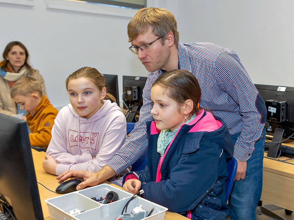 Lehrer Mathias Hildmann vom Geschwister-Scholl-Gymnasium erklärt Lotti (l.) und Larissa eine Roboter-Bauanleitung.