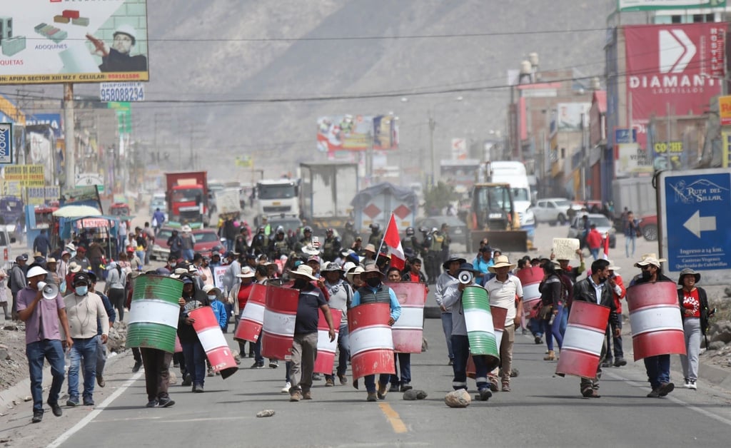 Demonstranten marschieren bei einem Protest gegen die Regierung von Präsidentin Boluarte mit behelfsmäßigen Schildern über eine Straße im peruanischen Arequipa.