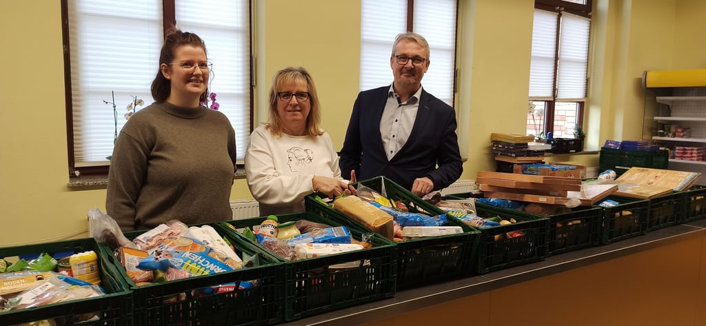 Antonia Weitz und Alexandra Franke zeigen Andreas Grobe vom Landesbetrieb für Bau und Liegenschaftsmanagement die Tafel in Buckau. Der Betrieb hatte den Erlös seiner Weihnachtstombola für die Tafel gespendet.