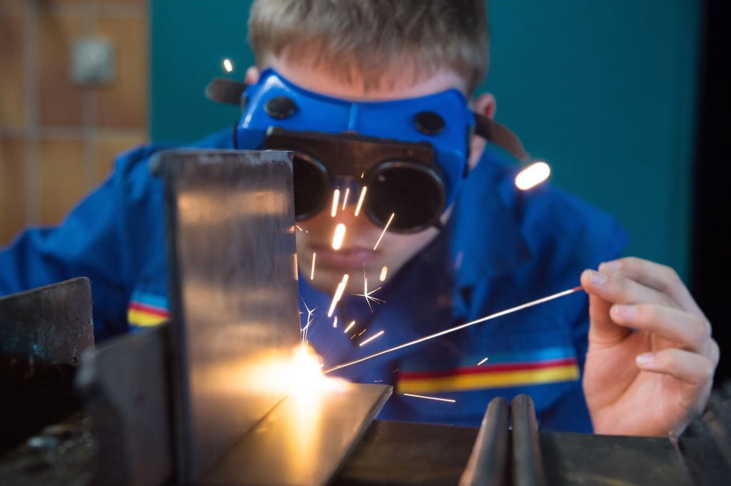 Ein Auszubildender demonstriert in einer Werkstatt das Gasschweißen. 