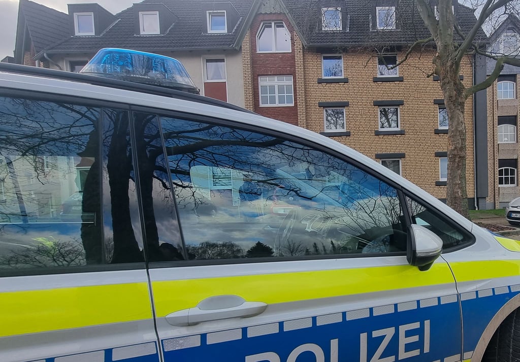 Ein Polizeiauto steht im Zuge von Ermittlungen vor einem Mehrfamilienhaus.