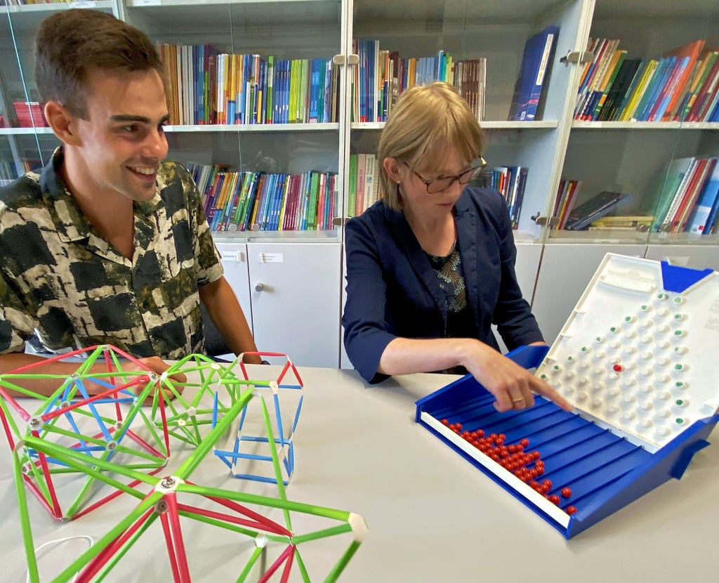 Nick Waldstädt und Uniprofessorin Stefanie Rach diskutieren an der Uni in Magdeburg über Material, mit dem Mathematik veranschaulicht wird. Neben geometrischen Objekten handelt es sich um das Galton-Brett. Dieses ist wichtig für die Einführung der Binomialverteilung im Bereich Stochastik.