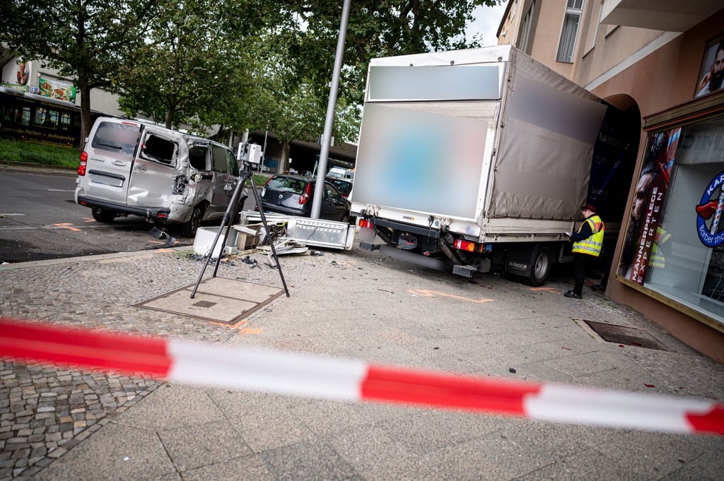 Ein Polizist steht neben einem Lastwagen, der in ein Haus gekracht ist.