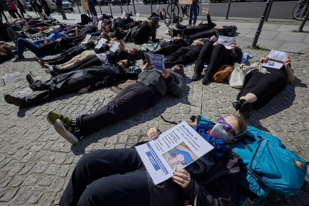 Demonstrierende machen vor dem Roten Rathaus aufmerksam auf die ME/CFS-Erkrankung.
