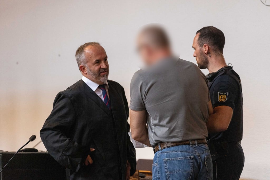 Der Angeklagte (M) spricht mit seinem Verteidiger (l) im Gericht.