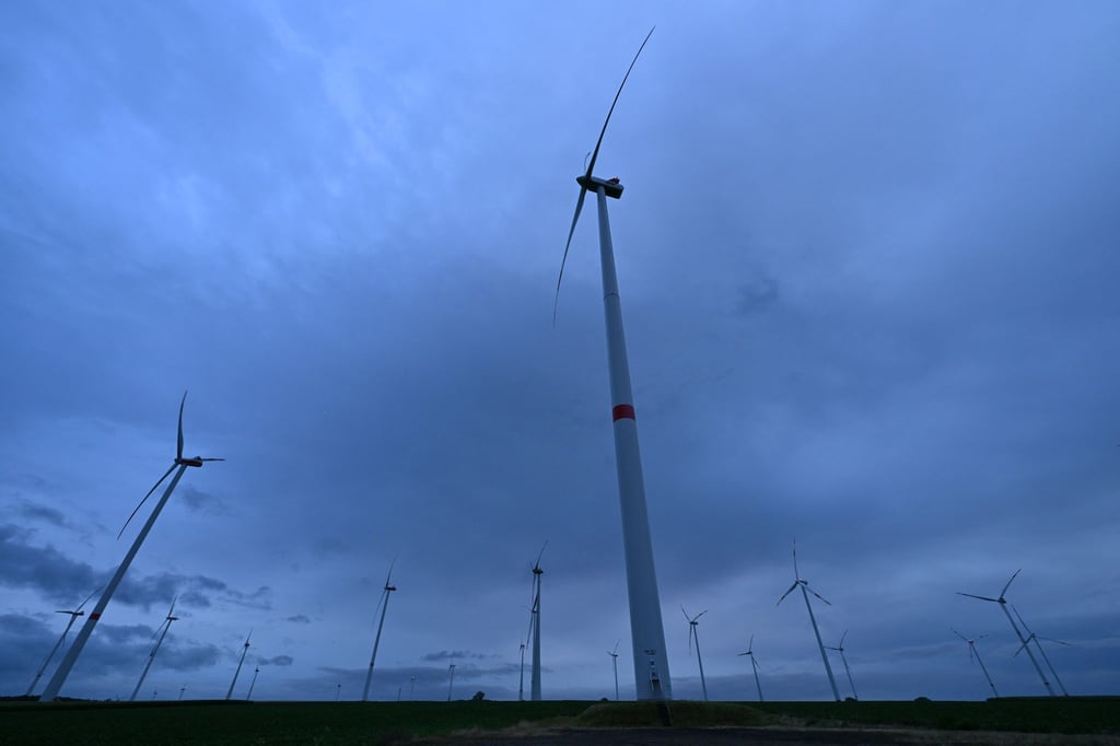 Regenwolken ziehen in der Morgendämmerung über einen Windpark bei Westhausen.