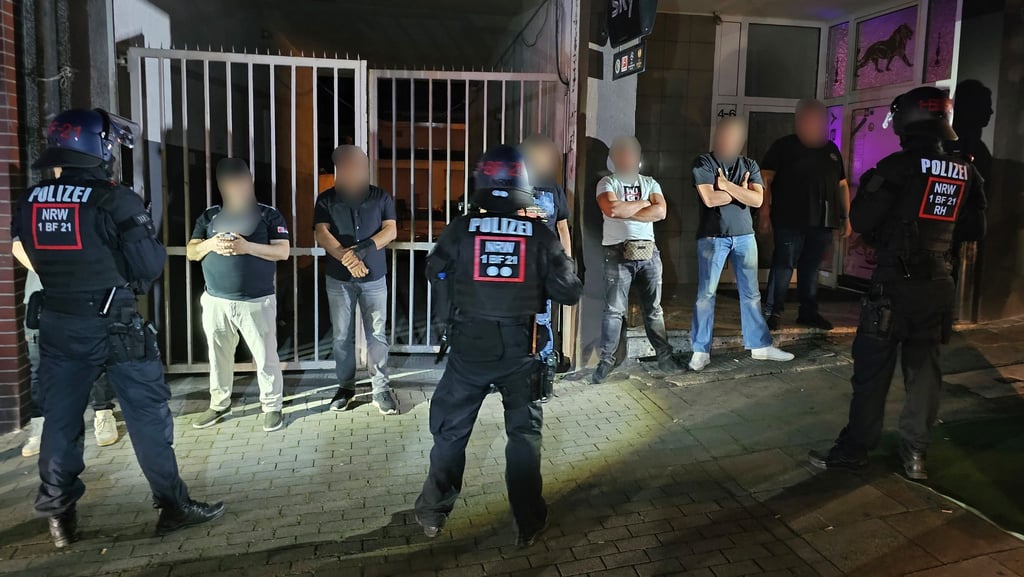 Polizisten bewachen Mitglieder einer der beteiligten Gruppen einer Schlägerei in der Innenstadt.
