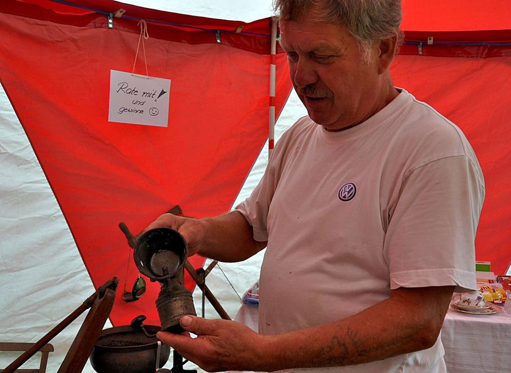 Gerd Molt präsentiert eine etwa 100 Jahre alte Fahrradlampe. Zum Dorffest zählte eine Ausstellung historischer Haushaltsgeräte.