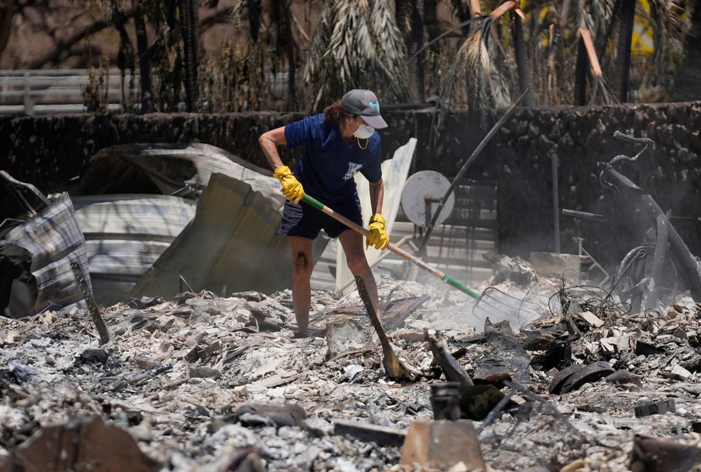 Eine Frau gräbt in Lahaina auf Hawaii in den Trümmern eines zerstörten Hauses.