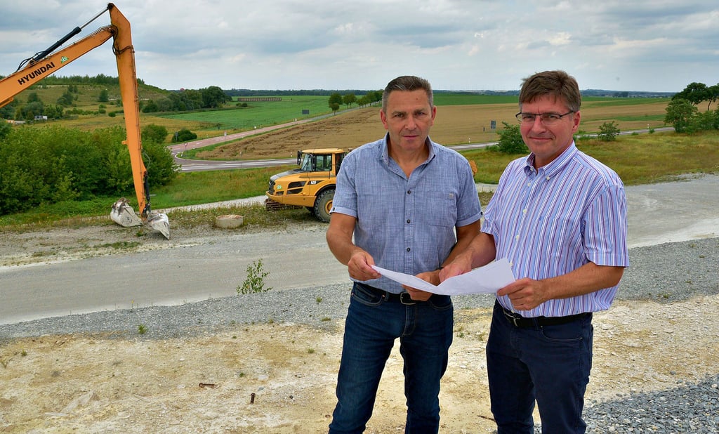 Solvay-Werkleiter Hugo Walravens (rechts) und Betriebsleiter Uwe Reh erläutern die Baupläne und Ausgleichsmaßnahmen. Im Hintergrund ist die Straße (L73) in Richtung Nienburg zu sehen. In diesem Bereich soll der neue Kalkteich entstehen.