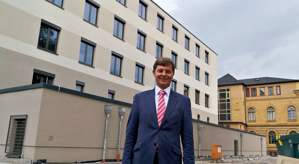 Gerichtspräsident Matthias Paterok zeigt das neue Gebäude, das später durch ein gläsernes Treppenhaus mit dem Altbau (r.) verbunden wird.