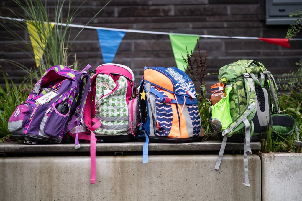 Vier Schulranzen stehen bei einer Einschulung in einer Grundschule auf einer Bank.