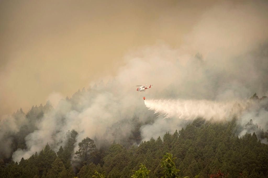 Ein Hubschrauber überfliegt einen Brand am Stadtrand von El Rosario während eines Löscheinsatzes.