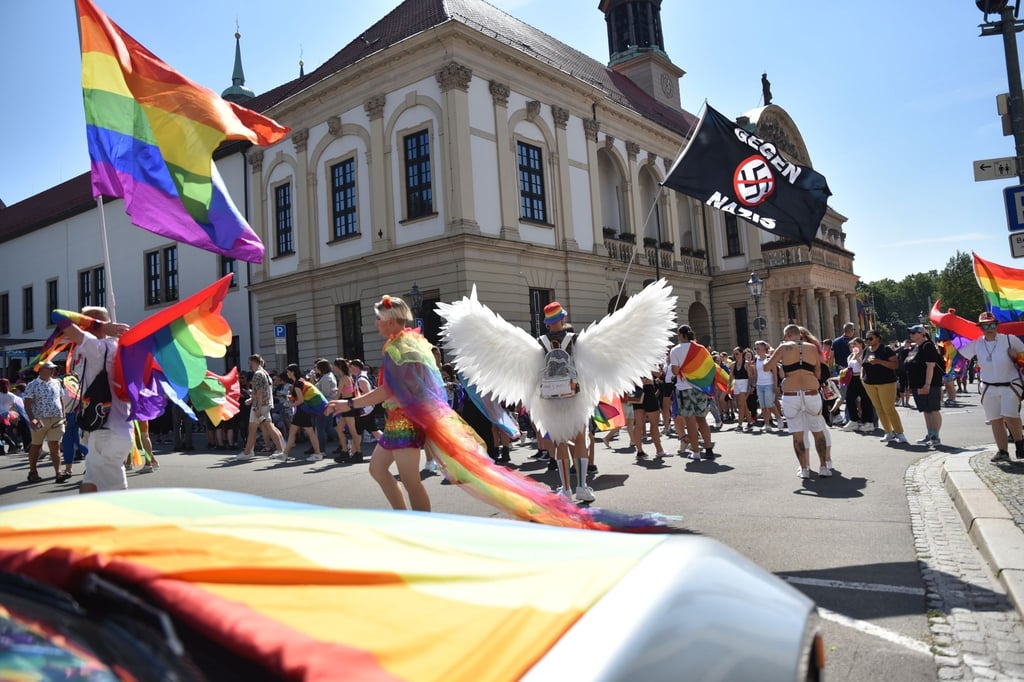 Ein CSD-Teilnehmer schwenkt eine Fahne mit der Schrift „Gegen Nazis“ vor dem Magdeburger Rathaus.